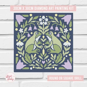 May include: A 30cm x 30cm diamond art painting kit featuring a pixelated design of two green frogs facing each other, surrounded by light purple bell-shaped flowers, white blossoms, and green foliage on a dark navy blue background.