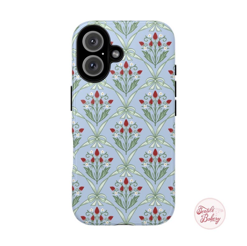 May include: A light blue phone case with a repeating floral design of red berries, white flowers, and green leaves, with bows. The case has a glossy finish and a camera cutout. The Textile Bakery logo is visible.