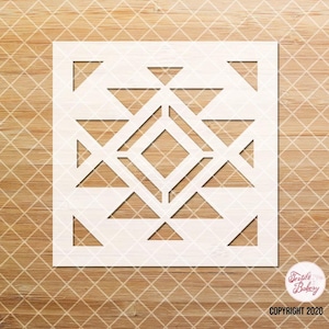 May include: White geometric stencil with a diamond shape in the center and triangles surrounding it. The stencil is on a wood background.