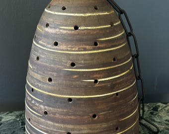 May include: A brown ceramic pendant light with a chain, featuring a textured, striped design and small holes throughout.