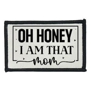 May include: A rectangular patch with the text "OH HONEY I AM THAT mom" in black on a white background. The patch has a black border and is likely an iron-on or sew-on patch for clothing or accessories.