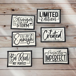 May include: Six white fabric patches with black text and borders. The patches feature inspirational quotes such as "Stronger Than The Storm", "You Are Enough", "Limited Edition", "Created With A Purpose", "Be Real Not Perfect", and "Perfectly Imperfect".