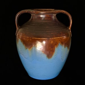 May include: A brown and blue ceramic vase with two handles. The vase has a brown glaze that drips down to a blue glaze.