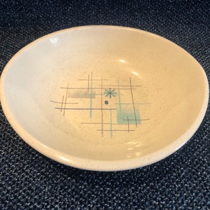May include: A white ceramic bowl with a geometric design in shades of blue and brown. The design features a grid pattern with a star in the center.