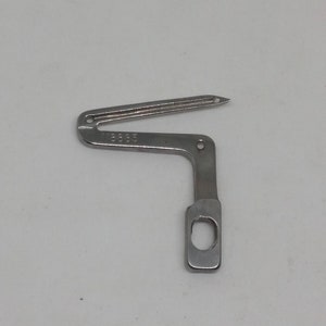 May include: A silver sewing machine foot with a small hole and a number "100055" engraved on the side.