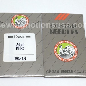 May include: Two grey paper packets of Organ Needles for sewing, knitting, and felting. The left packet features a white label with 10pcs, 24x1, DHx1, and 90/14 printed in black. The right packet displays the Organ Needles logo and company name.