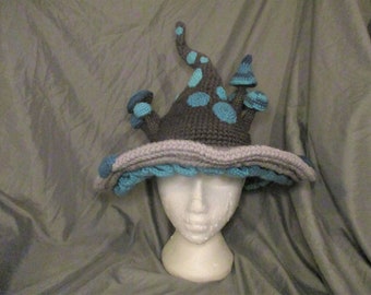 May include: A crocheted hat shaped like a mushroom house with a gray base and blue and gray accents.