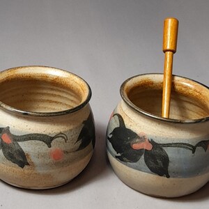 May include: Two small ceramic bowls with a blue, brown and white floral design. One bowl has a wooden stirring stick inside.