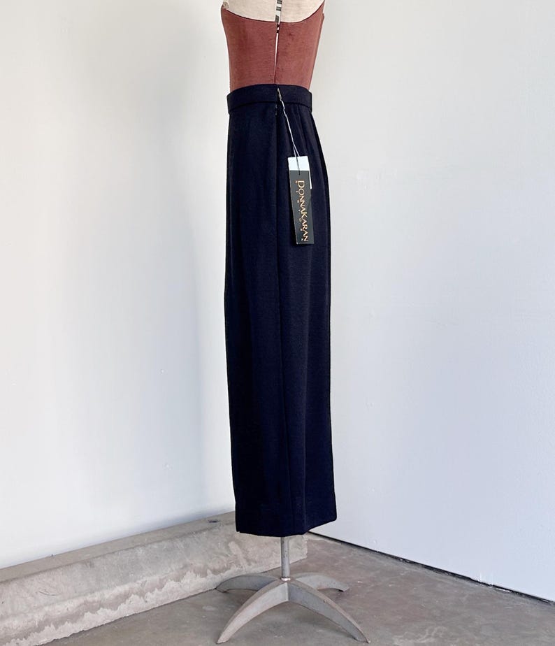 Pode incluir: Uma saia maxi preta com silhueta reta. A saia &eacute; feita de um tecido liso e leve e tem um design simples e elegante. A saia est&aacute; em um manequim e tem uma etiqueta que diz "Donna Karan".