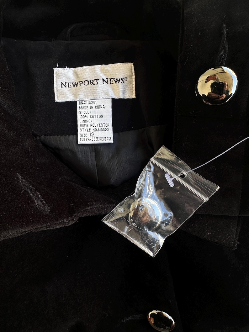 May include: Black velvet jacket with large silver buttons. The label reads "NEWPORT NEWS" and includes details about the shell, lining, and size 12. A new button is attached in a plastic bag.