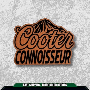 May include: A wooden sign with the words "Cooter Connoisseur" in black lettering. The word "Cooter" is in a stylized font, and the word "Connoisseur" is in a block font. A mountain range graphic is above the word "Cooter".