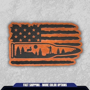 May include: A brown and black patch featuring an American flag design with a bullet shape. The bullet design includes a silhouette of a hunter, deer, trees, and a sun. The text "FAST SHIPPING - MORE COLOR OPTIONS" is at the bottom.