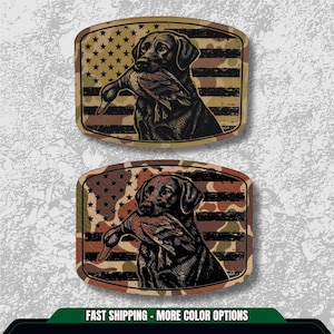 May include: Two rectangular patches featuring a black Labrador Retriever holding a duck in its mouth. The background is a camouflage pattern with an American flag design. The patches have a distressed, vintage look.