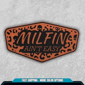 May include: An orange and black patch with the words "MILFIN AIN'T EASY" in a stylized font. The patch has a leopard print border and small skull graphics.