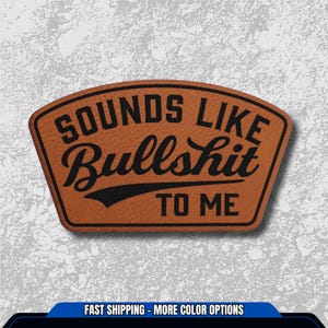 May include: A brown leather patch with the phrase "SOUNDS LIKE Bullshit TO ME" in black, stylized lettering. The patch has a curved top and a black banner beneath the word "Bullshit".
