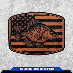 May include: A distressed-style patch featuring a detailed illustration of a fish, set against a backdrop of the American flag. The fish is brown with black accents, and the flag has a vintage, worn appearance. The patch is rectangular with rounded corners.