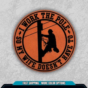 May include: Orange round sticker with a black silhouette of a lineman climbing a utility pole. The text around the edge reads "I WORK THE POLE SO MY WIFE DOESN'T HAVE TO".