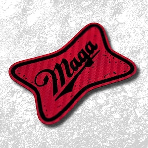 May include: A red patch with a black border and the word "Maga" in a stylized black font. The patch has a textured surface and a unique shape, with a slight shadow effect.
