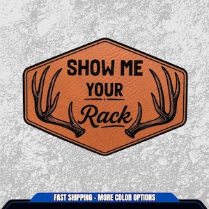 May include: A brown, hexagonal patch with the text "SHOW ME YOUR Rack" in black. The patch features black antler illustrations on each side. The background is a textured, light gray.