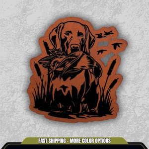 May include: A brown and black illustration of a hunting dog holding a duck in its mouth, with cattails and flying ducks in the background. The image has the text "FAST SHIPPING - MORE COLOR OPTIONS" at the bottom.