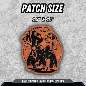 Puede incluir: Un parche marr&oacute;n y negro con la cabeza de un perro y una silueta de escena de caza. El parche mide 6,35 cm x 5,33 cm. El texto "PATCH SIZE" est&aacute; en la parte superior.