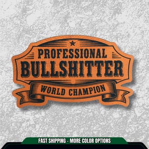 May include: An orange and black sticker with the words "PROFESSIONAL BULLSHITTER WORLD CHAMPION" in bold, stylized font. The text is set within a decorative, vintage-style frame with a star at the top.