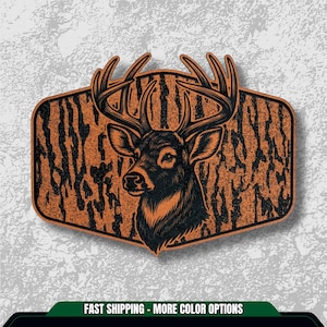 May include: A deer head illustration in black and brown, set against a textured background. The deer has large antlers and is framed within a shield-shaped design. The image has a rustic, outdoorsy feel.