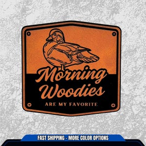 May include: A rectangular sticker with an orange background and a black border. The sticker features a detailed illustration of a duck and the words "Morning Woodies ARE MY FAVORITE" in a stylized font.