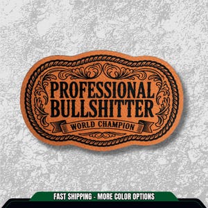 May include: An orange and black oval-shaped patch with the words "PROFESSIONAL BULLSHITTER WORLD CHAMPION" in a decorative font. The patch has a rope-like border and ornate scrollwork.