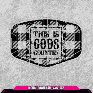 May include: Black and white plaid design with the text "THIS IS GODS COUNTRY" in a rectangular shape. The text is surrounded by barbed wire. The background is a textured gray.