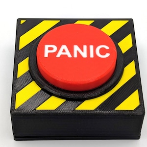 Może przedstawiać: Czerwony przycisk z napisem "PANIC" nadrukowanym na biało, umieszczony w czarnym pudełku z żółto-czarnymi paskami ostrzegawczymi.