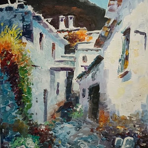 Puede incluir: Una pintura de una calle estrecha y sinuosa en un pueblo. Los edificios son blancos con acentos azules y hay una planta verde exuberante creciendo en el lado izquierdo de la calle. El cielo es azul y hay montañas en el fondo.