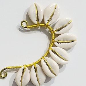 May include: A gold wire ear cuff with white seashells attached. The wire is wrapped around the seashells, creating a curved shape.