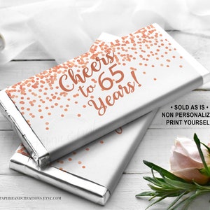 Pode incluir: Embrulhos de barra de chocolate imprimíveis com um design de confete dourado rosa e o texto "Cheers to 65 Years!" Esses embrulhos são vendidos como estão e não são personalizados. Você precisará imprimi-los você mesmo.