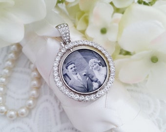 May include: A silver pendant with a round photo of a couple in a black and white photo. The pendant is surrounded by a circle of clear rhinestones.