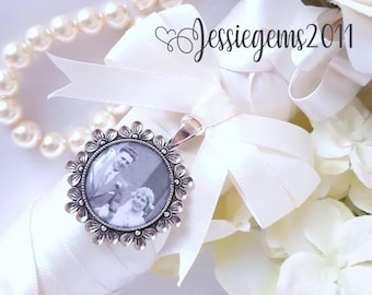May include: A white bridal bouquet with a silver photo charm attached. The charm features a black and white photo of a couple.