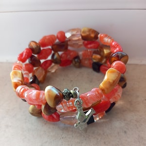 Peut inclure: Un bracelet multi-rangs composé de perles de verre orange, brun et transparent. Le bracelet est orné d'un charme en argent en forme d'oiseau.