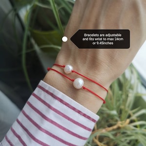 May include: Two red string bracelets with white pearl charms. The bracelets are adjustable and fit wrists up to 9.45 inches.