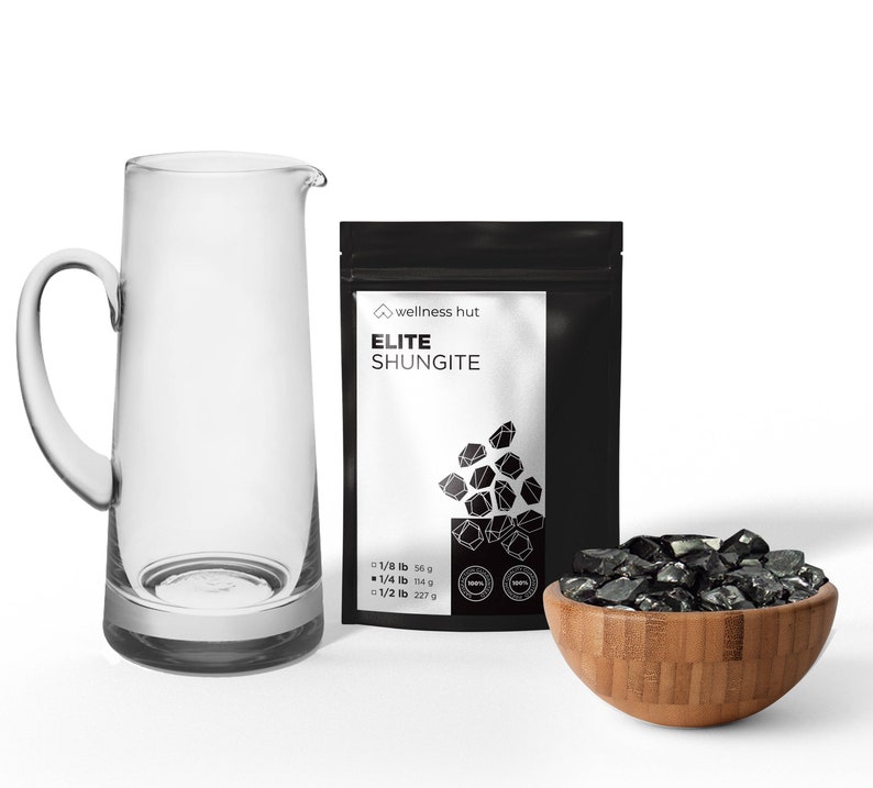 May include: A black bag with the text "wellness hut ELITE SHUNGITE" and a picture of black shungite stones. The bag is next to a clear glass jug and a bowl of black shungite stones.