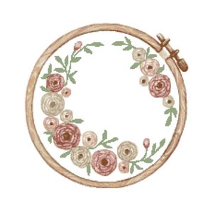Peut inclure: Un cercle de broderie en bois avec un motif floral. Le cercle est rempli de fleurs roses et blanches et de feuilles vertes.