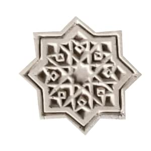 Può includere: Una piastrella di ceramica bianca con un intricato disegno a stella a otto punte. La stella è composta da forme geometriche più piccole, creando un motivo complesso e simmetrico.