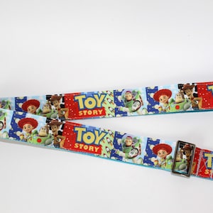 Puede incluir: Dos correas azules y rojas con tem&aacute;tica de Toy Story con cierres met&aacute;licos plateados. Las correas presentan im&aacute;genes de Woody, Buzz Lightyear y el logotipo de Toy Story. Las correas est&aacute;n dise&ntilde;adas para una bolsa.