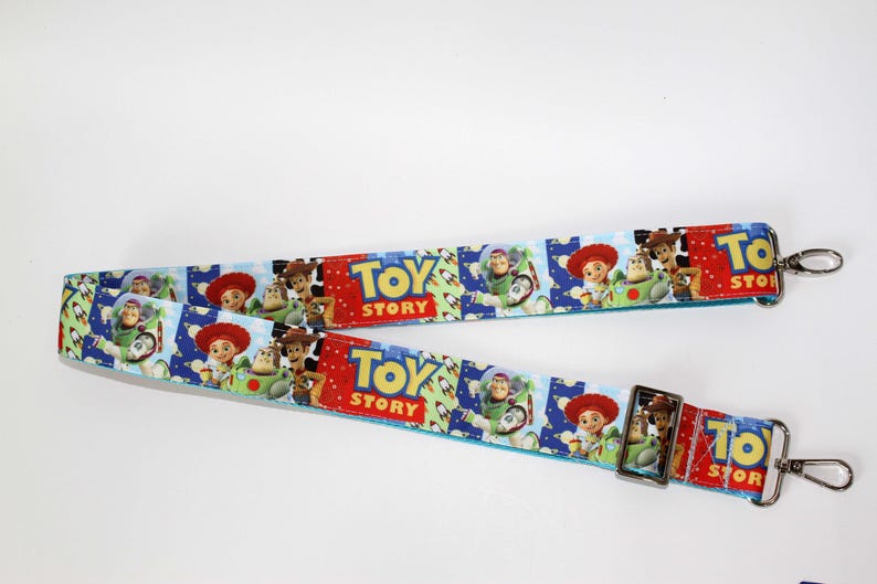 Puede incluir: Dos correas azules y rojas con tem&aacute;tica de Toy Story con cierres met&aacute;licos plateados. Las correas presentan im&aacute;genes de Woody, Buzz Lightyear y el logotipo de Toy Story. Las correas est&aacute;n dise&ntilde;adas para una bolsa.