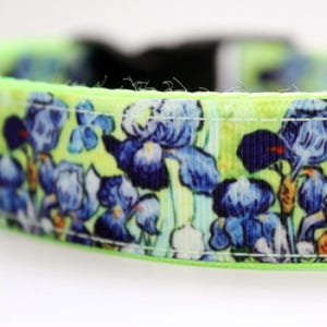 May include: A dog collar featuring a floral pattern of blue irises on a yellow and green background. The collar has a bright neon green edge and a black buckle. The design is reminiscent of a painting.
