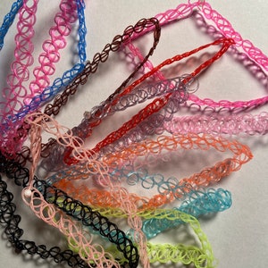 Könnte beinhalten: Eine Sammlung bunter Plastik-Choker-Halsketten in verschiedenen Farbtönen von Rosa, Blau, Rot, Orange, Gelb und Schwarz.
