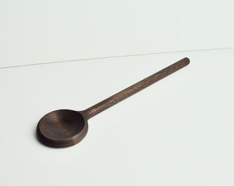 May include: A dark brown wooden spoon with a rounded bowl and a long handle.