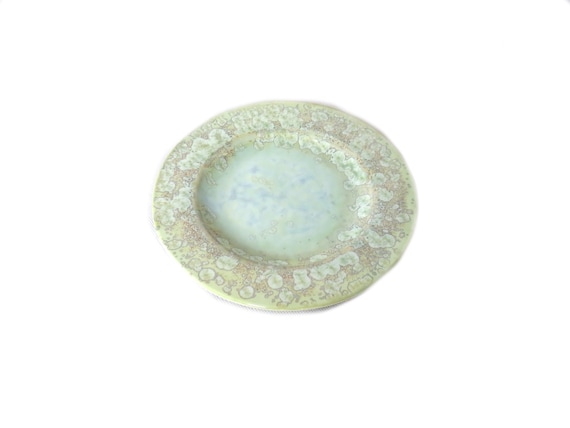 A pale green plate with a stylised floral pattern /  designed by  Max Studio