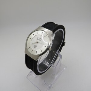 May include: A silver wristwatch with a white face and black rubber band. The watch face has the text "Eau Thermale Av&egrave;ne" printed on it.