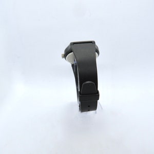 K&ouml;nnte beinhalten: Eine schwarze Armbanduhr mit rechteckigem Zifferblatt und schwarzem Armband. Die Uhr hat ein schlichtes, modernes Design mit einem Schnallenverschluss. Die Uhr wird vor einem wei&szlig;en Hintergrund pr&auml;sentiert.