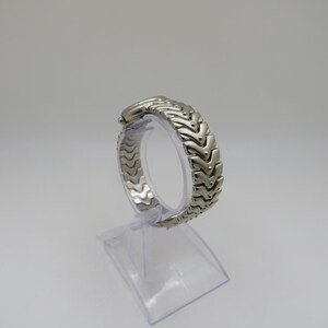 K&ouml;nnte beinhalten: Silberfarbenes Armband f&uuml;r eine Uhr mit einem einzigartigen, ineinandergreifenden Chevron-Design.
